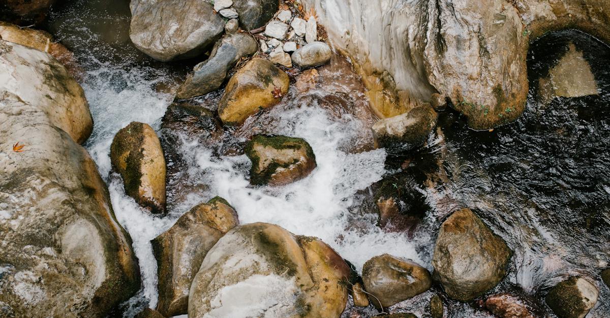 An enchanting photograph captures the serene beauty of streaming water as it gracefully navigates its way through a rugged terrain of ancient rocks.
