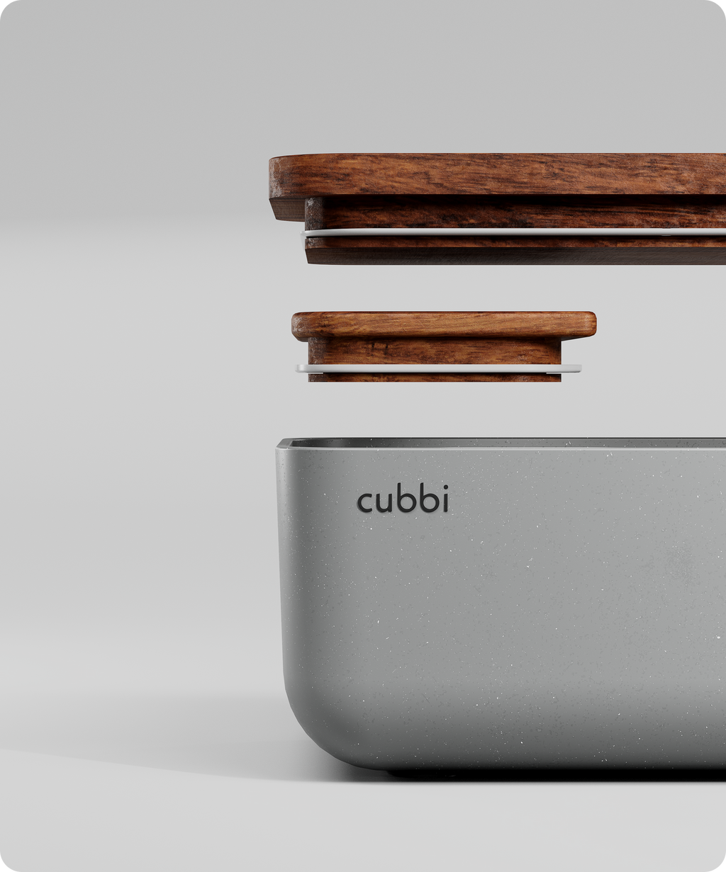 A white Cubbi airtight box with a wooden lid sits on a white background. The box has a silicone seal and a tray  for storing personal items.  Cubbi is a brand of storage containers.