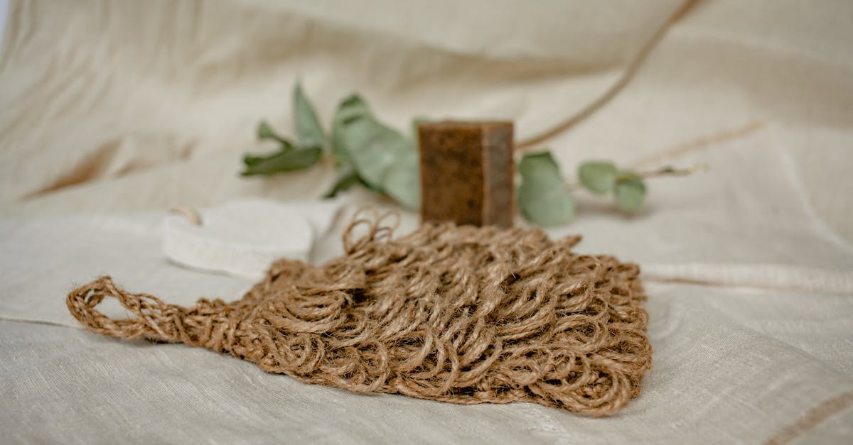 A jute soap holder placed on a table beside a bar soap.