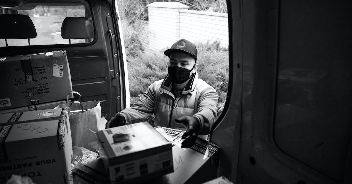 A photo of courier unloading a box of package from the delivery van.