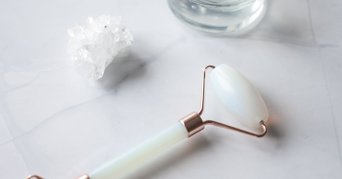 A facial roller with clear quartz crystals on the white surface.