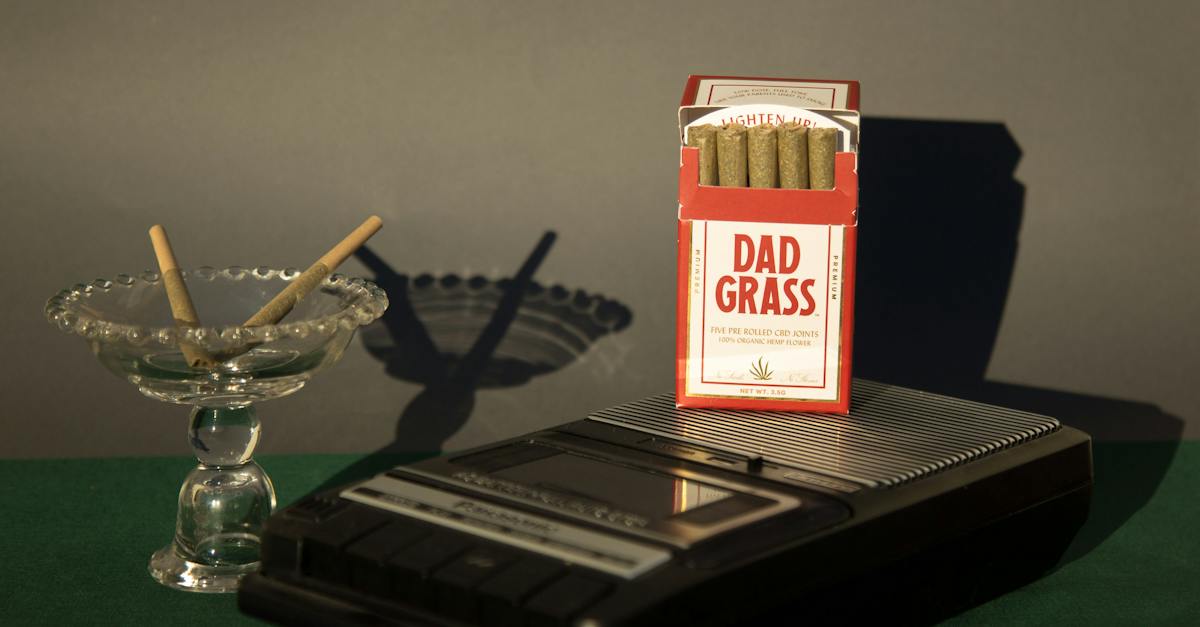 In a nostalgic tableau, a vintage tape recorder stands proudly beside a pack of DAD GRASS, evoking a sense of bygone eras and timeless memories.