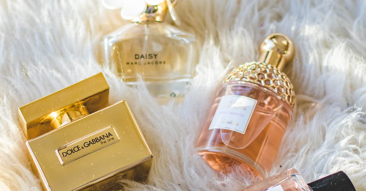 Three bottles of perfume are grouped together on top of a soft, fluffy fur stole or throw blanket.